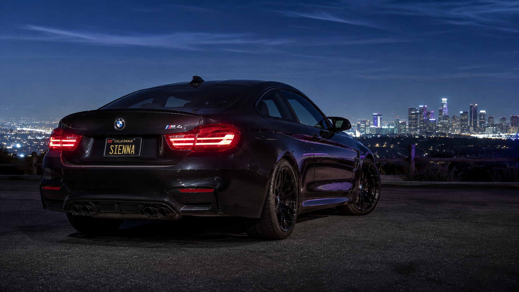 Sienna's black BMW F82 M4 overlooking the Los Angeles skyline at blue hour