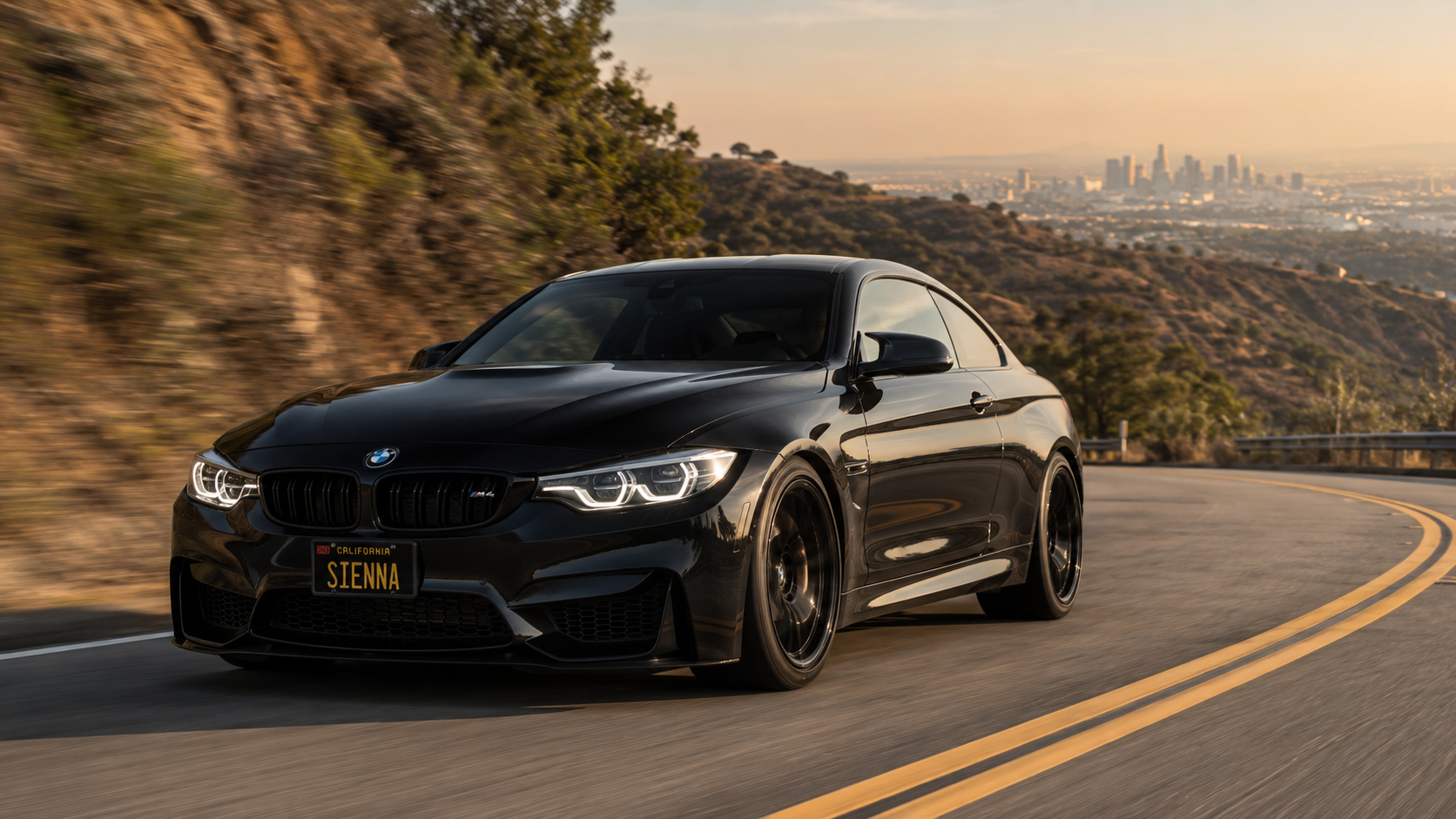 Sienna's black BMW F82 M4 driving through a Los Angeles canyon at golden hour